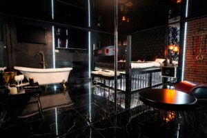 Nowoczesny pokój z rurą do poledance, wanną wolnostojącą i akcesoriami erotycznymi