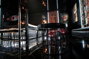 Pokój ze stolikiem i akcesoriami do poledance, na ścianach obrazy kobiet