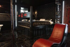 Sypialnia z łóżkiem z klatką i czerwoną leżanką