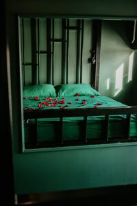 odbijające się w lustrze łóżko, na nim rozsypane płatki róż